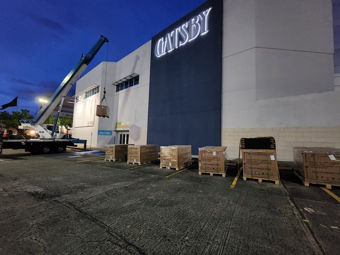 Grúa izando paneles solares de noche durante la instalación comercial de Gatsby